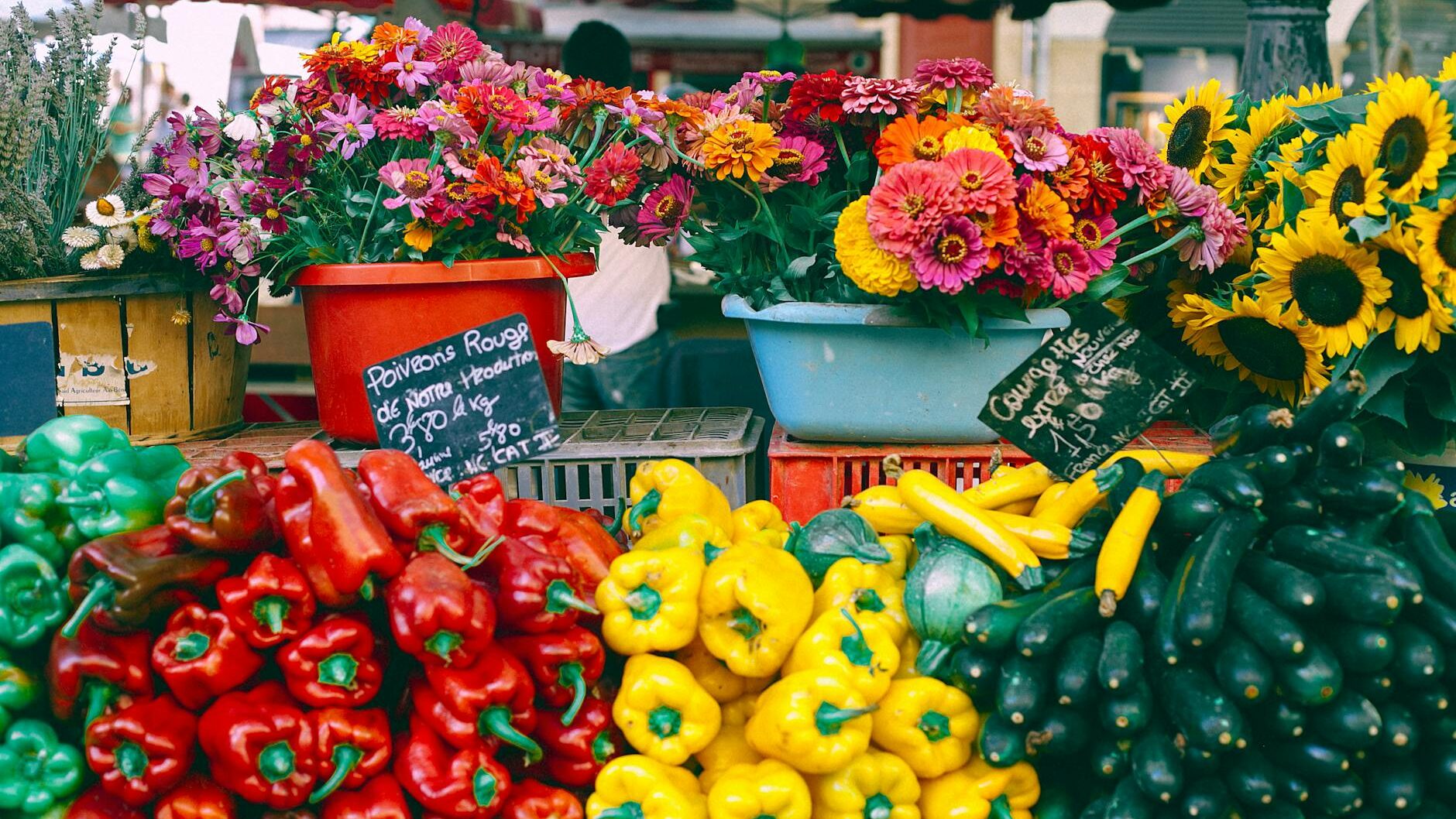 assorted vegetables and blooming flowers at market